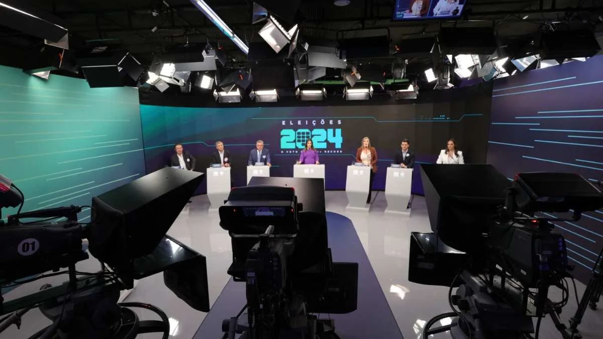 Manuella Niclewicz com os seis candidatos participantes do debate no estúdio