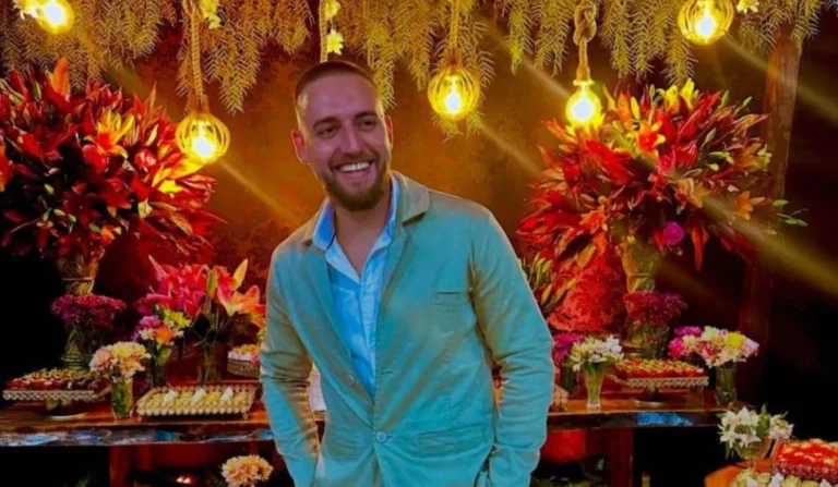 homem sorrindo com decoração de flores ao fundo