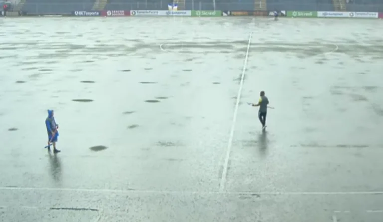 homens tentando secar o gramado com um rodinho