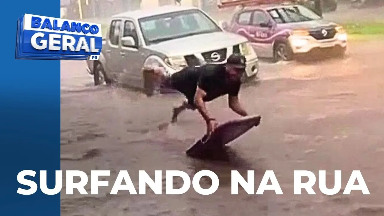 Tempestade: homem surfa na rua alagada, em meio a um temporal