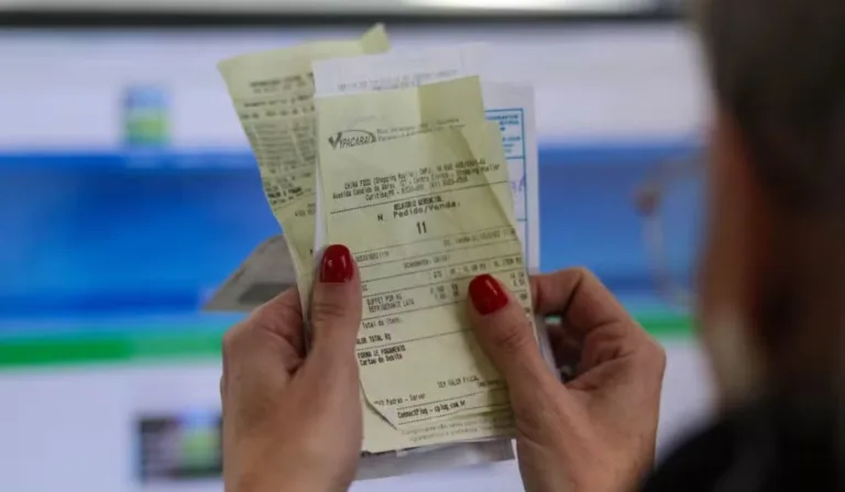 mulher segurando notas fiscais em frente ao site do nota parana