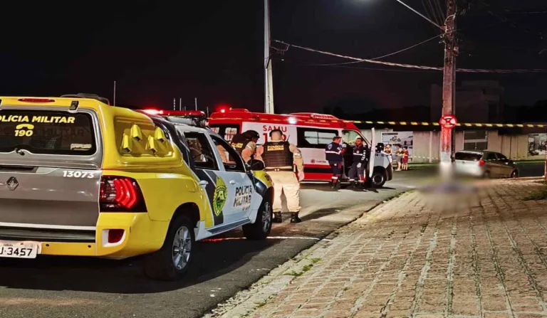 Viaturas da Polícia Militar e do Samu atendendo ocorrência de homem morto com disparos, caído na calçada.