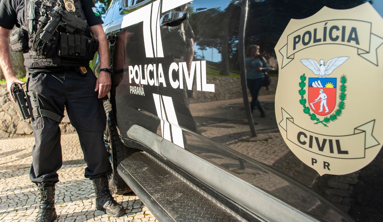 Viatura da Polícia Civil com policial ao lado