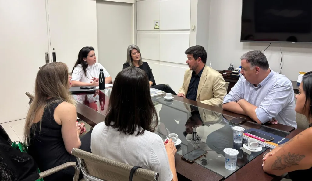 foto de sete pessoas sentadas em volta de uma mesa de vidro