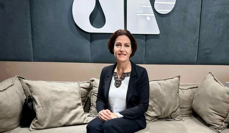 A jornalista Cristina Graeml sentada no sofa, com a logo da Jovem Pan atrás.