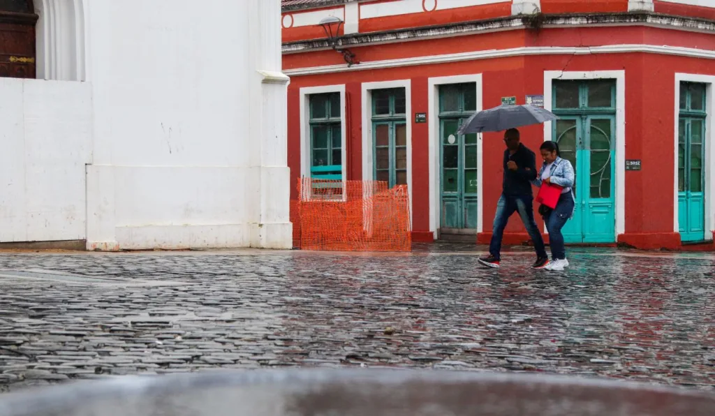 duas pessoas com sombrinhas durante chuva em Curitiba