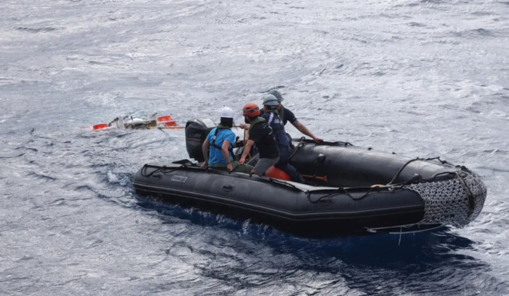 Quatro pessoas dentro de um bote, no meio do oceano.