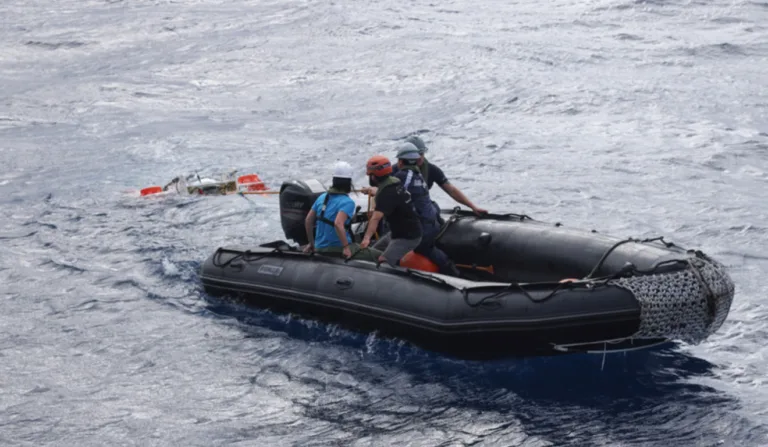 Quatro pessoas dentro de um bote, no meio do oceano.