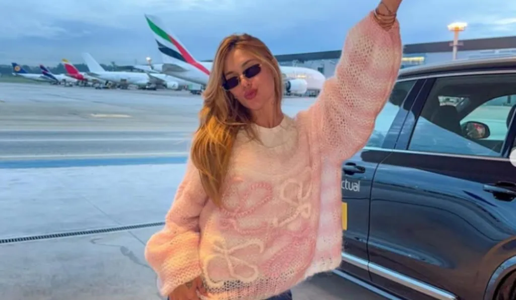 virginia posando em frente de aeroporto usando oculosescuros