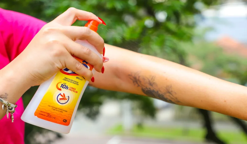 Mulher utilizando repelente nos braços