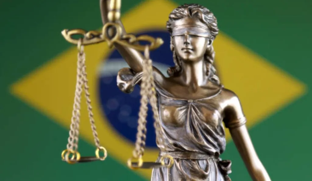estatua de justiça em frente a bandeira do brasil