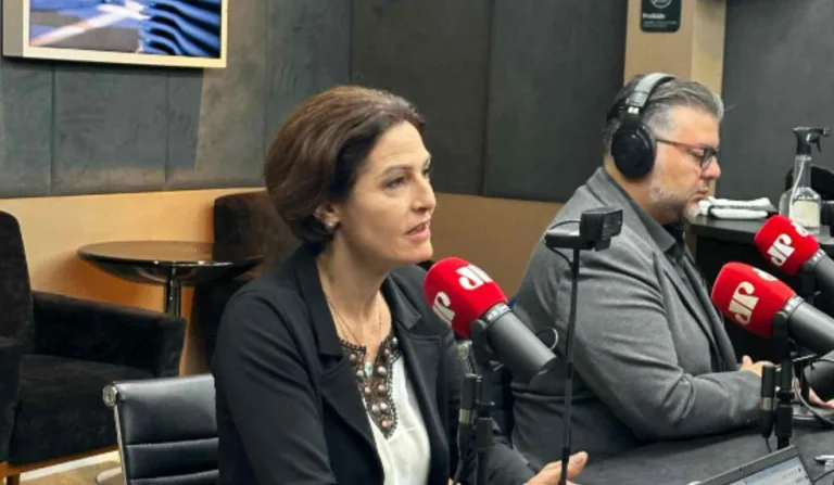 A jornalista Cristina Graeml, ao lado do jornalista Karlos Kohlbach, falando no microfone da Jovem Pan News.