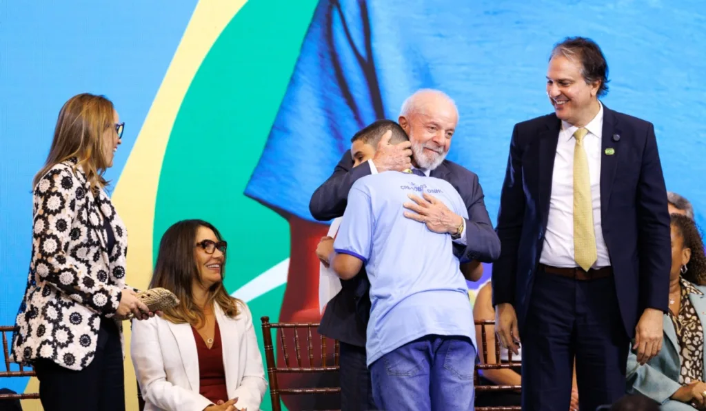 A imagem mostra o presidente Lula abraçando uma criança.