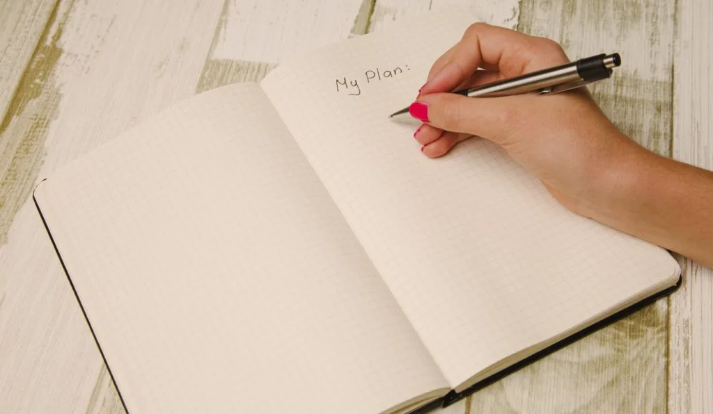 foto de uma pessoa escrevendo em um caderno