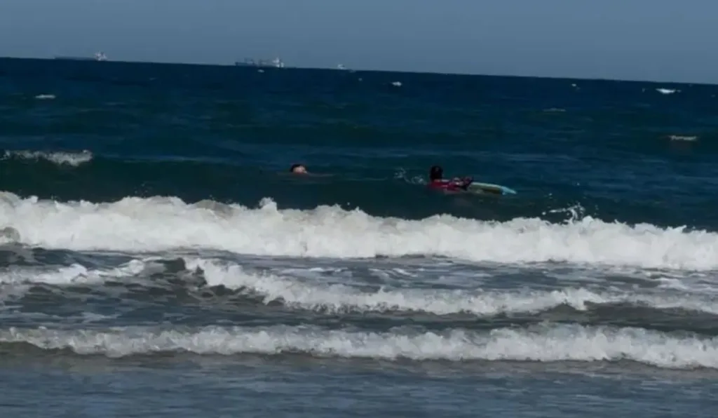 Mar de Pontal do Paraná e banhista sendo socorrido por PM