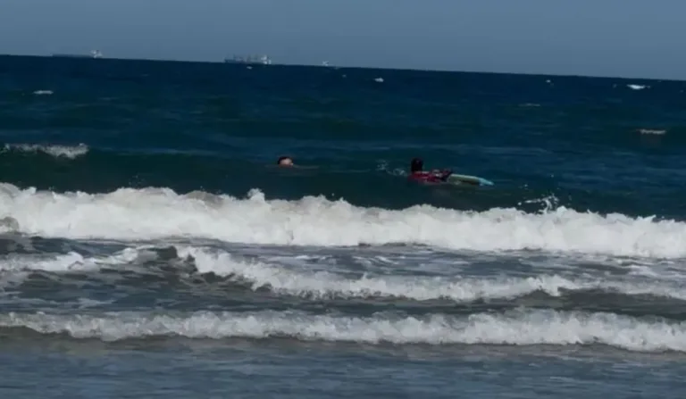 Mar de Pontal do Paraná e banhista sendo socorrido por PM