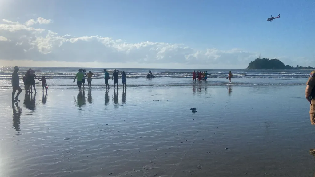 Praia com equipe dos Bombeiros e helicóptero fazendo buscas
