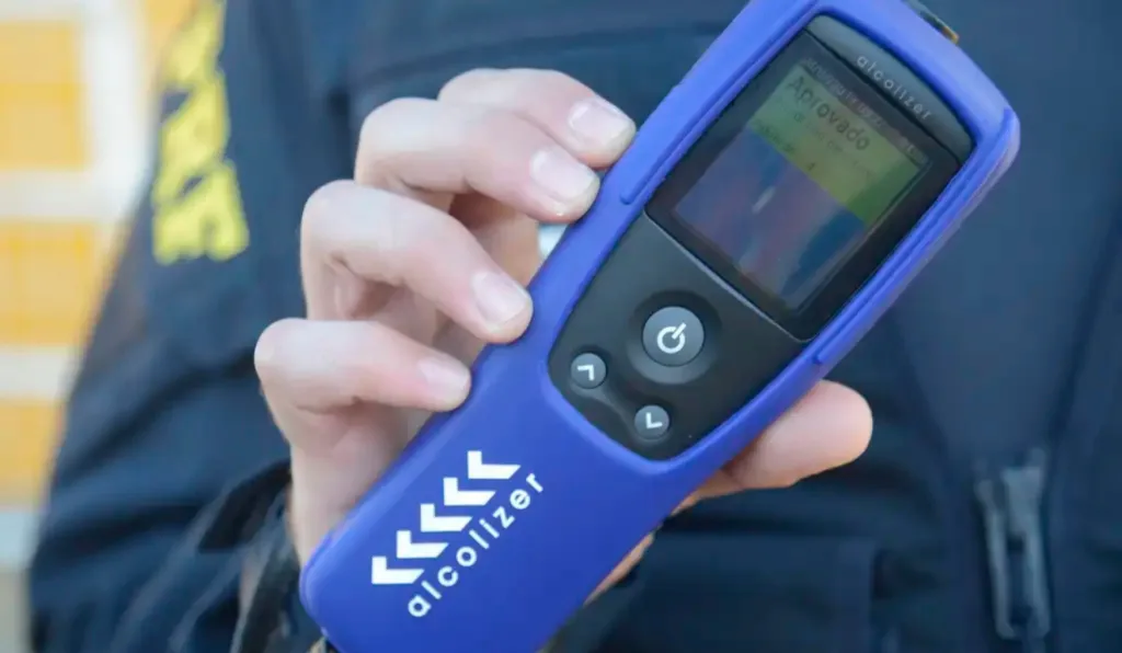 Um policial segurando o teste do bafômetro.