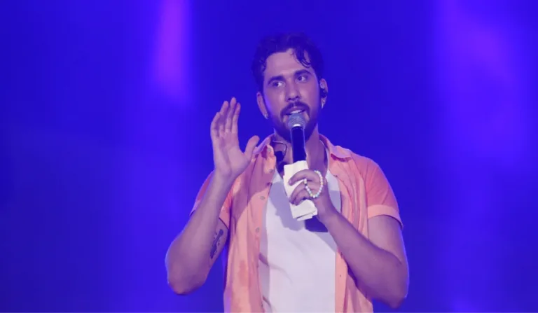 Gustavo Mioto de camisa laranja em show.