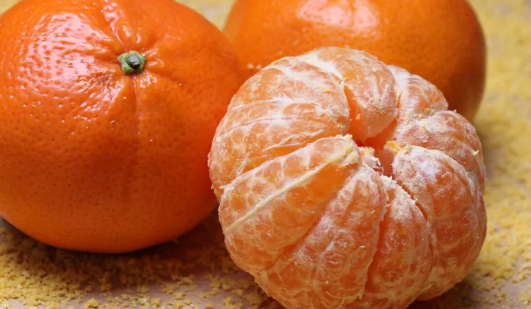 Foto de três tangerinas, e uma sem casca.