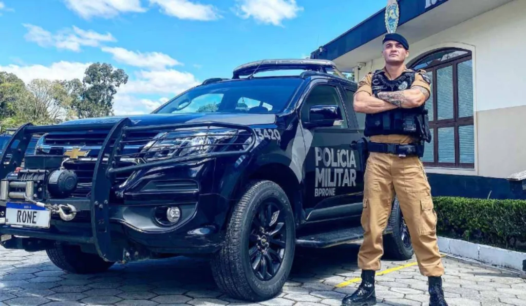 Policial ao lado de viatura