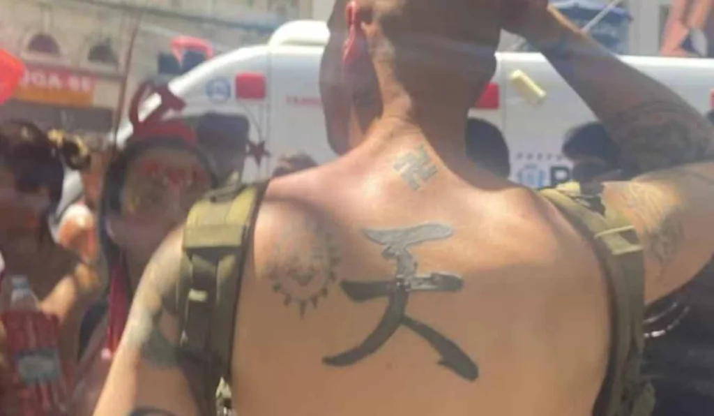 Costas do estrangeiro em camisa e símbolos nazistas tatuados