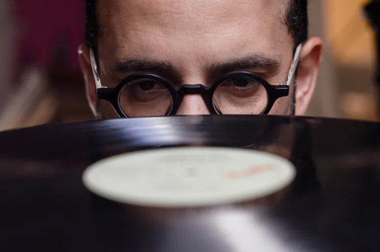 Dabliu olhando um disco de vinil com metade do rosto coberto pelo rosto