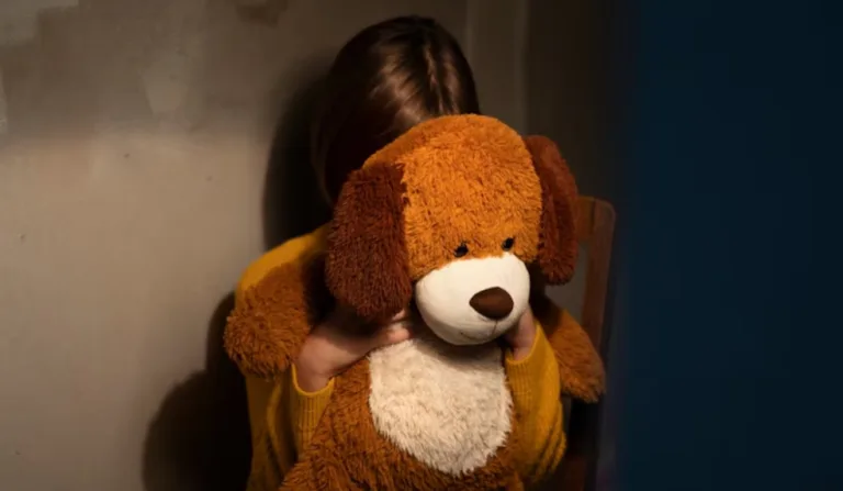 Criança triste com urso na frente