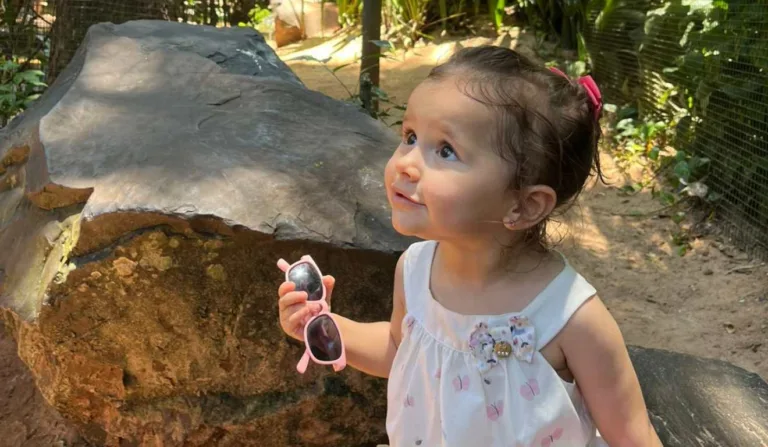 bebê com óculos escuro na mão