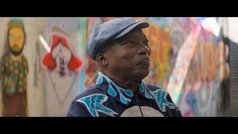 Milton Nascimento está de perfil com uma boina e um leve sorriso no rosto