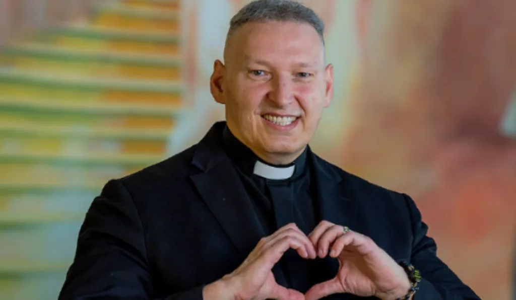 Homem de cabelo branco fazendo um sinal de coração com as mãos