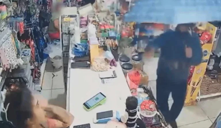 Homem apontando arma para mulher no balcão de pet shop