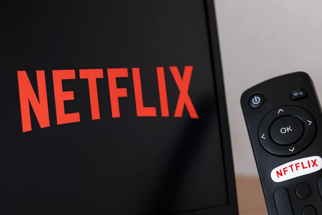 Logotipo da Netflix exibido em tela grande com fundo escuro, simulando interface de TV ou projetor em ambiente doméstico.