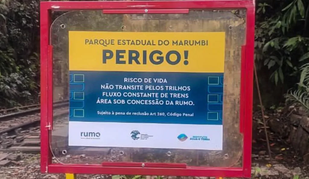 placa alertando para a proibição de andar pelos trilhos
