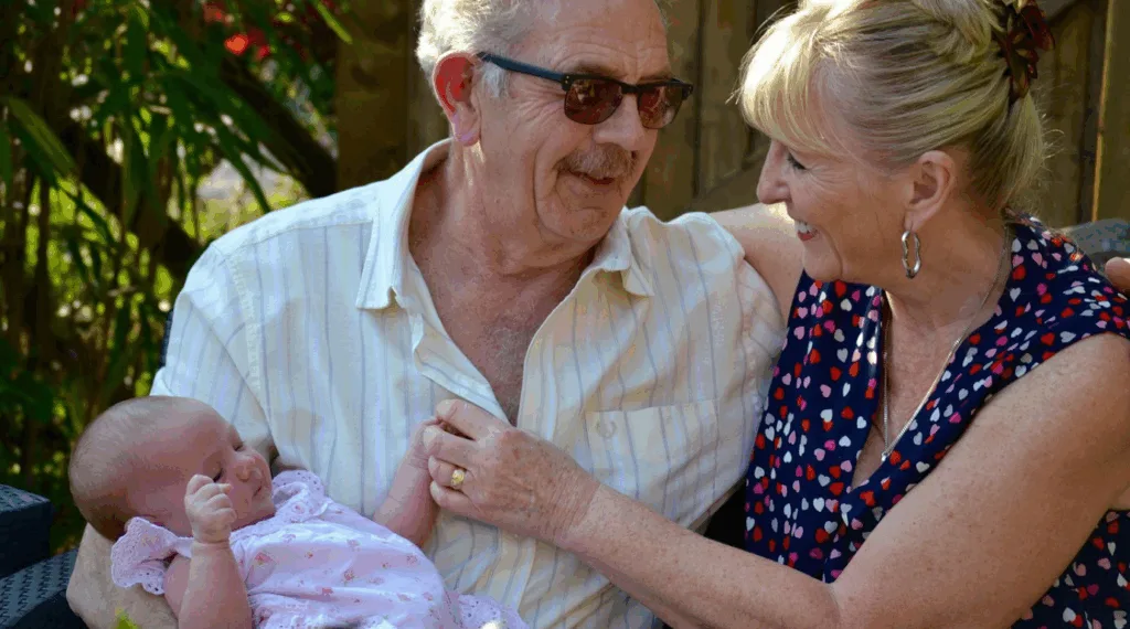 avô e avó segurando neto e sorrindo