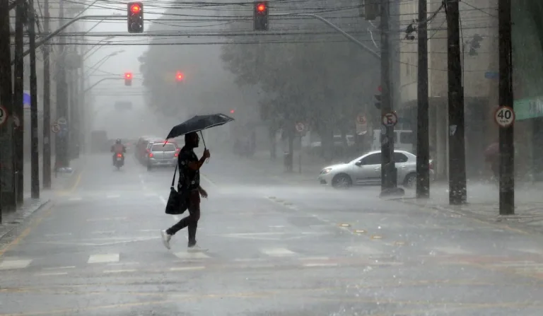 pessoa de sombrinha andando na chuva para ilustrar a chegada do ciclone extratropical