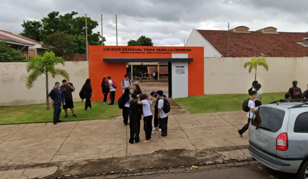foto da fachada de uma escola com estudantes na frente. professor teria oferecido dinheiro aos alunos para que agredissem outro estudante