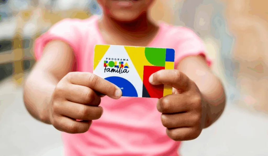 Uma criança segurando o cartão do Bolsa Família