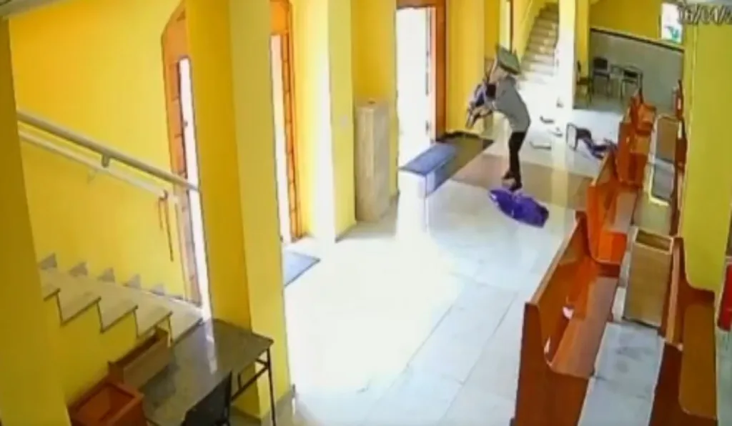 Homem destruindo imagens de santos na igreja.