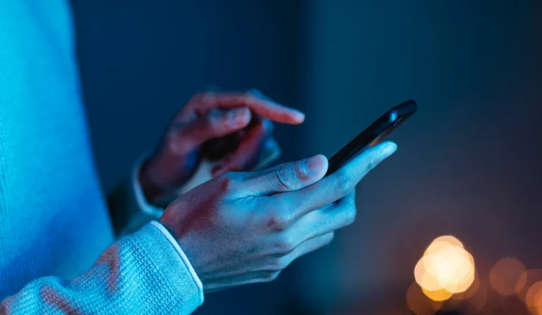 Mão com celular nas mãos.