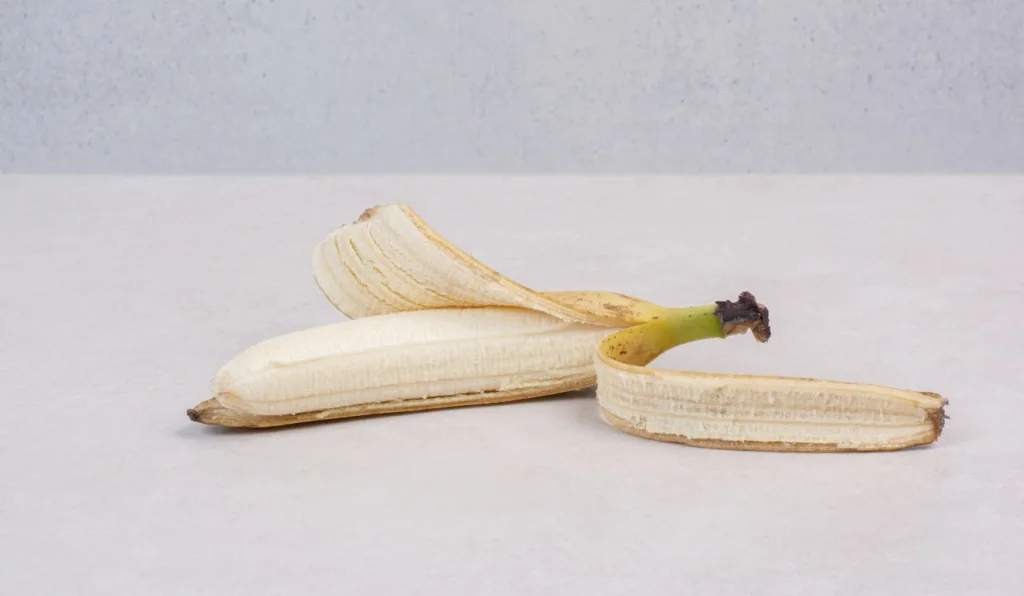 Banana com casca aberta em cima da mesa.