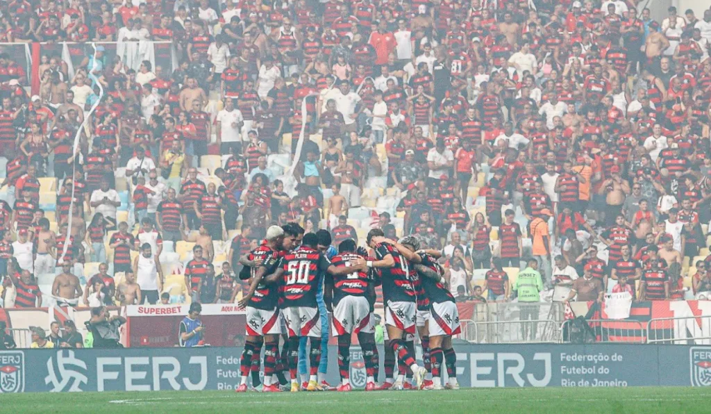 Time do Flamengo reunido com a torcida ao fundo