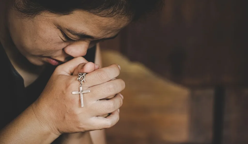 mulher fazendo a oração de são cipriano segurando um terço