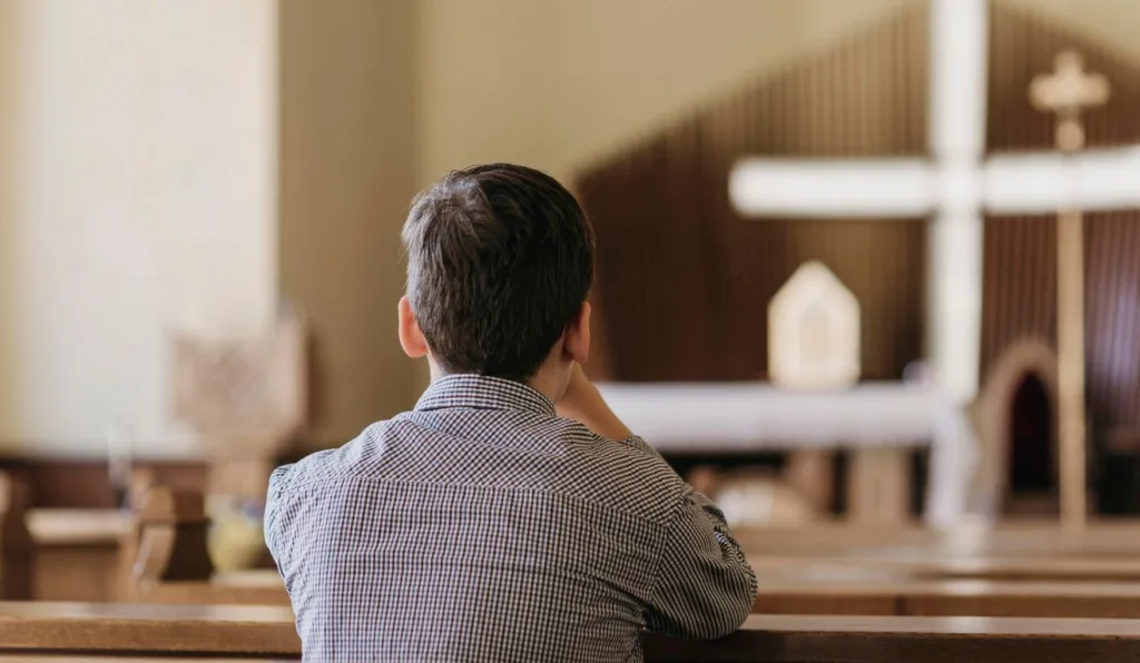 homem orando em uma igreja católica