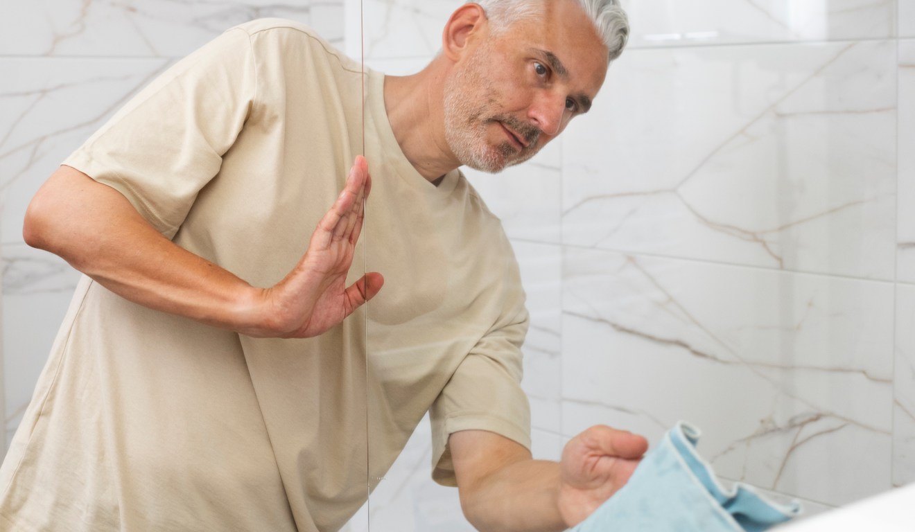 homem limpando vidro de box do banheiro