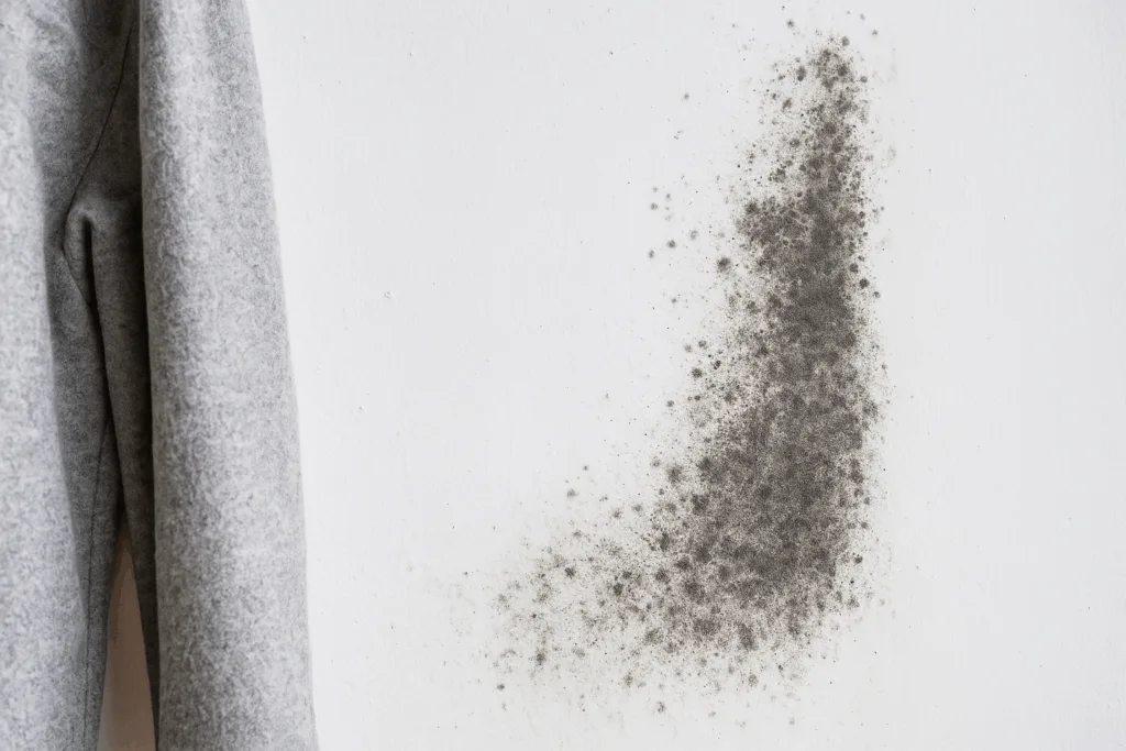 Mancha de mofo escura em parede branca com tecido próximo ao foco de umidade