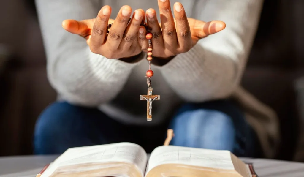 mulher segurando terço e realizando oração de arcanjo miguel