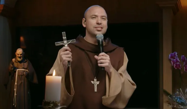 Frei Gilson segurando um microfone e uma cruz