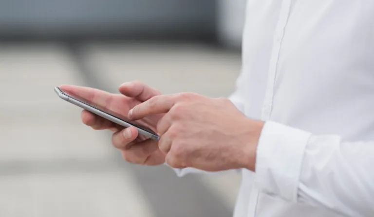 Mãos utilizando o celular.