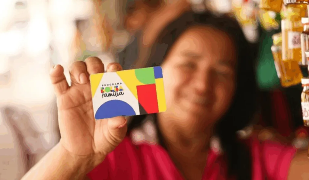 Uma mulher segurando o cartão do Bolsa Família